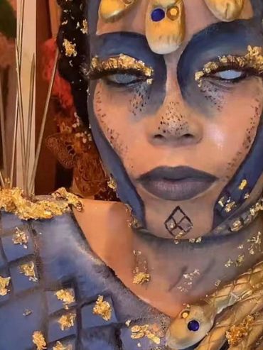 Close-up of a person with elaborate blue and gold face and body paint.
