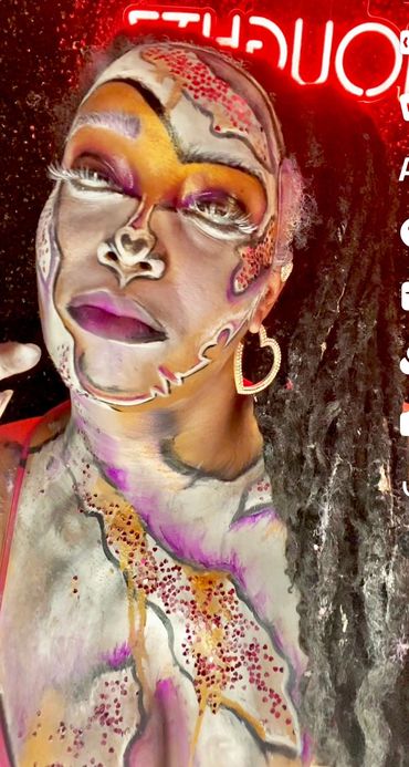 Person with vibrant abstract face and body paint under neon light.