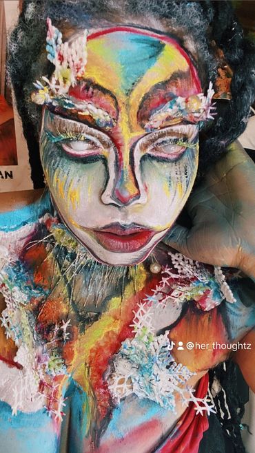 Person with vibrant, artistic face and body paint featuring snowflake details.