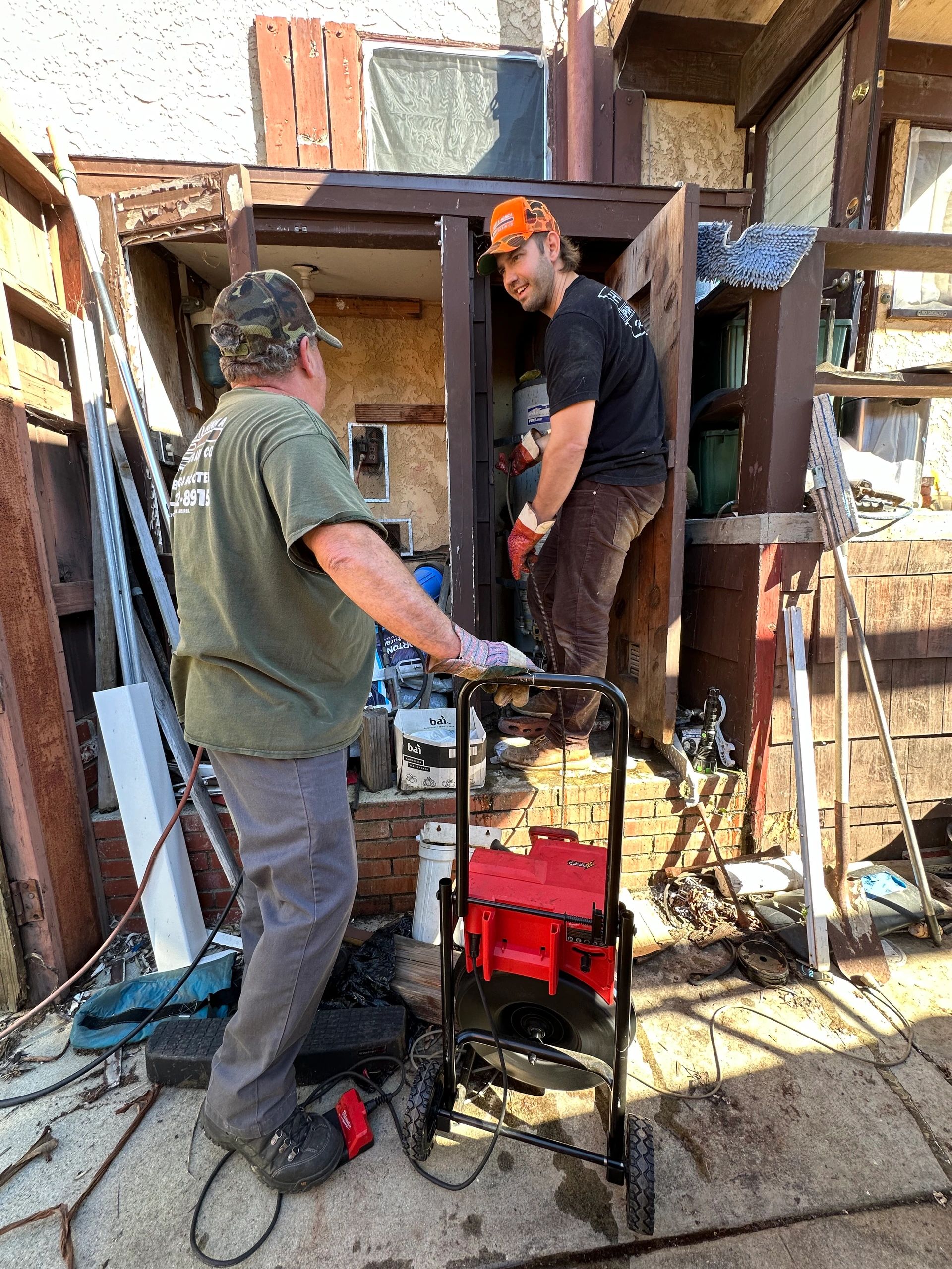 Oliver and Stelios Unclogging a drain from a hidden cleanout.