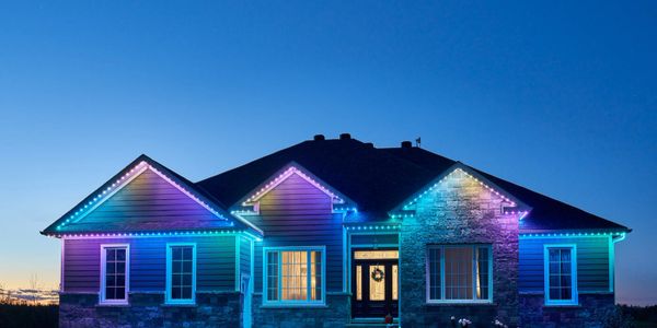A house decorated with colorful LED lights at dusk.