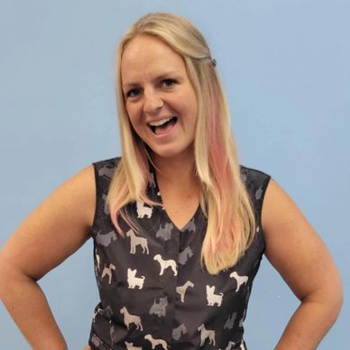 Smiling woman in dog-print sleeveless top against blue background.
