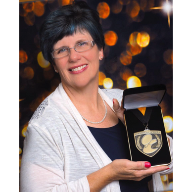 Woman proudly holding an award medal in a presentation box.