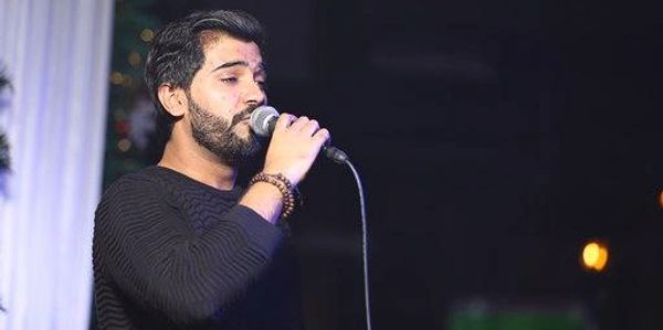 Man singing into a microphone on stage.