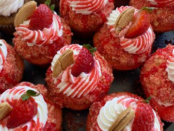 Strawberry cupcakes topped with cream, fresh strawberries, and mini cookies.