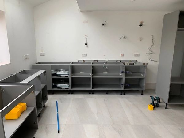 Starting to install a new kitchen, putting kitchen units into place.
