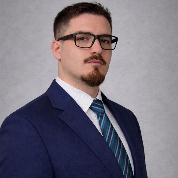 Professional man in suit and glasses posing confidently.