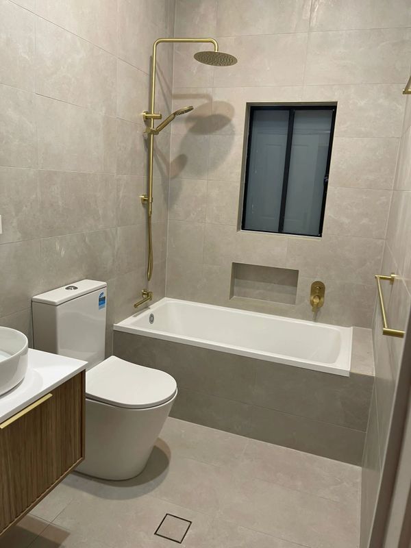Built-in bathtub with overflow, paired with the Misha Brush Gold double shower head and tap diverter.