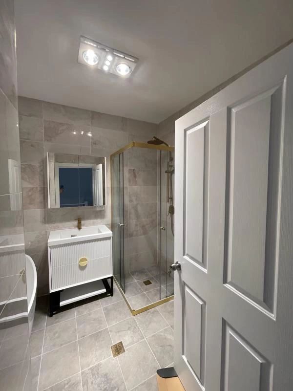 Complete bathroom reno with a white flute vanity and marble look tiles offering simple yet luxurious