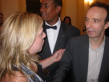 Three people engaged in a conversation at a formal event.
