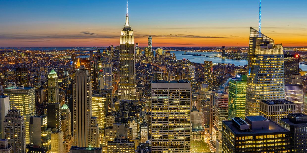 Skyline di New York al tramonto con l'Empire State Building illuminato.