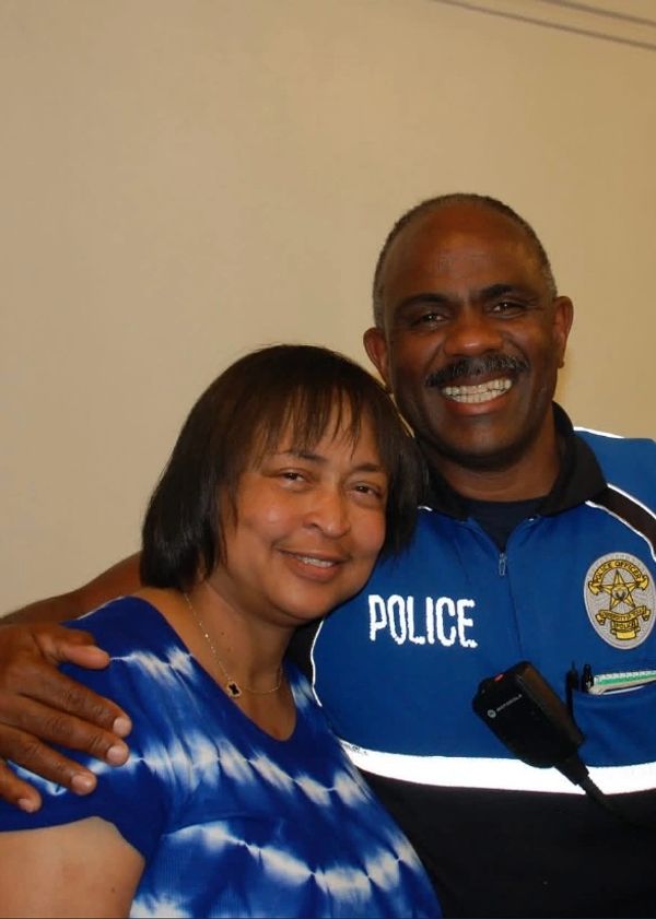 Smiling police officer and woman posing closely together indoors.