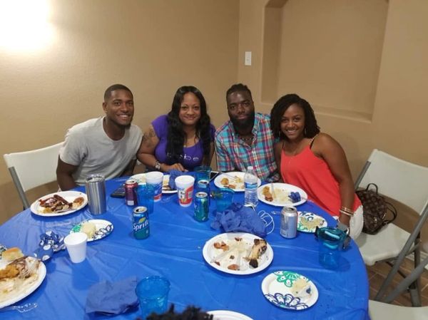 Four people enjoying a meal together at a blue-covered table indoors.