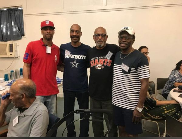 Four men standing and posing for a photo in a casual indoor setting.