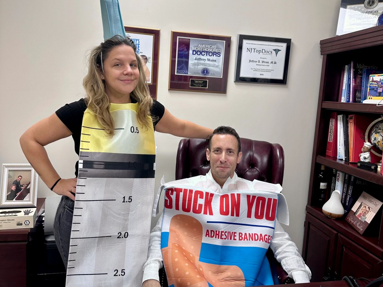 Two people in adhesive bandage and measuring tape costumes posing in an office.