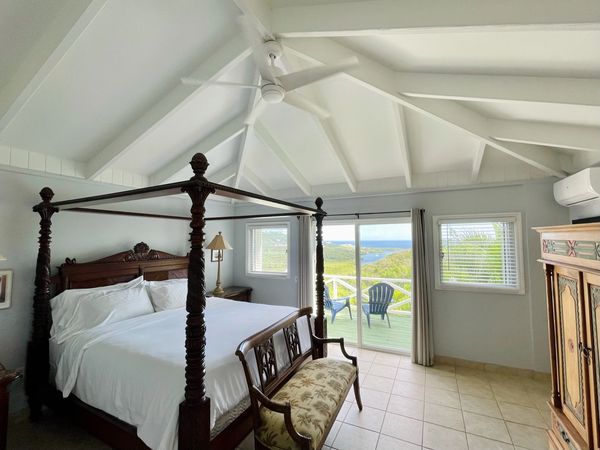 Elegant bedroom with a four-poster bed and ocean view balcony.