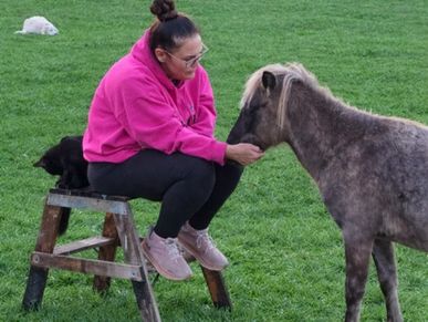 woman Sitting in green pasture with a horse