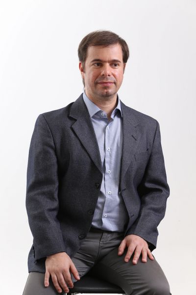 Man in a blazer sitting against a white background.