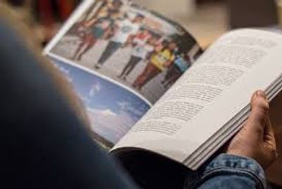 Person reading a magazine with images and text.