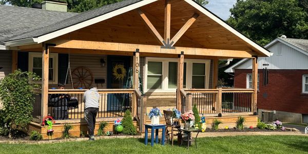 Cozy wooden porch with plants and outdoor seating on a sunny day.