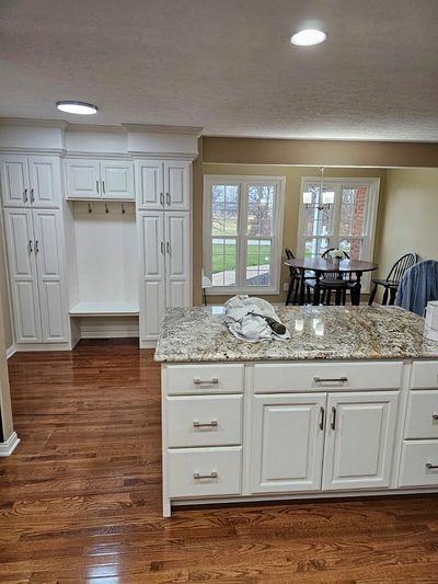 Bright kitchen with white cabinets, granite countertop, and hardwood floor.