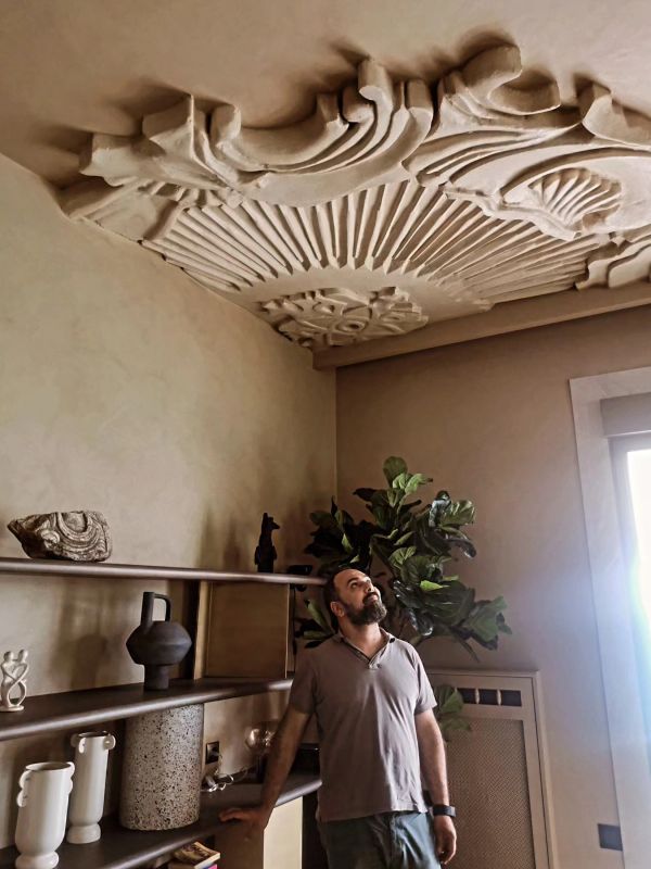 Man admiring intricate ceiling design in a cozy room.
