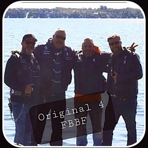 Four men in biker vests posing by a lake, labeled Original 4 FBBF.