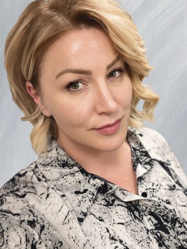 Portrait of a woman with blonde hair and patterned blouse.