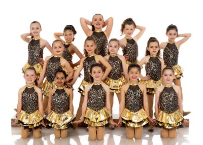 Group of young dancers in gold and black costumes.