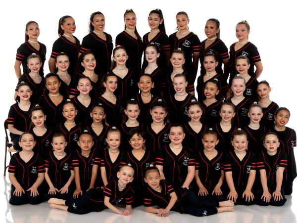 Large group of girls in black dance uniforms posing for a photo.