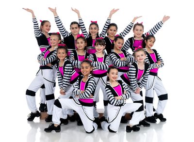 Young ballerinas in tutus smiling for a group photo

