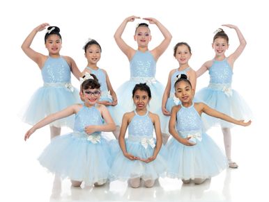 Children in blue tutus standing in formation for a ballet group picture

