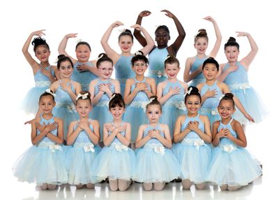 Group of young ballerinas in light blue tutus posing for a photo.