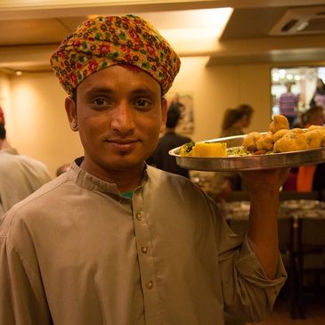 Man in traditional attire holding a plate of snacks.