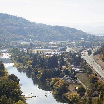 A scenic river flowing alongside a highway with hills in the background.