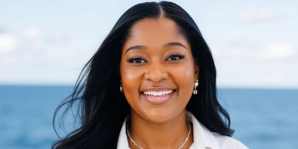 Smiling woman with long black hair against a blue ocean background.