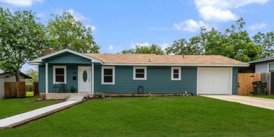 Blue single-story house with a well-maintained lawn and attached garage.