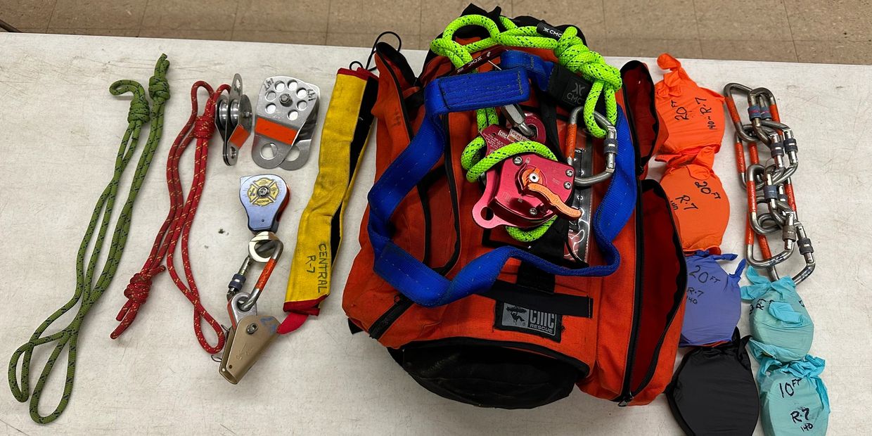 Rescue gear including ropes, pulleys, and harness on a table.