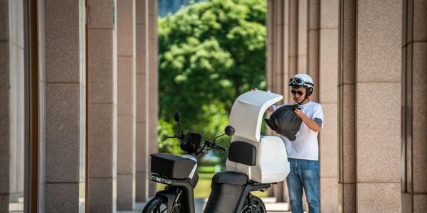A man is putting something into the cargo box of a cargo electric scooter