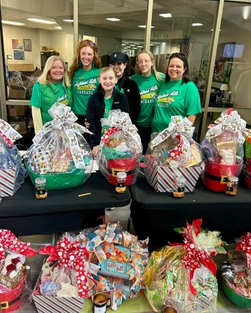 Group of women standing behind gift baskets with ribbons.