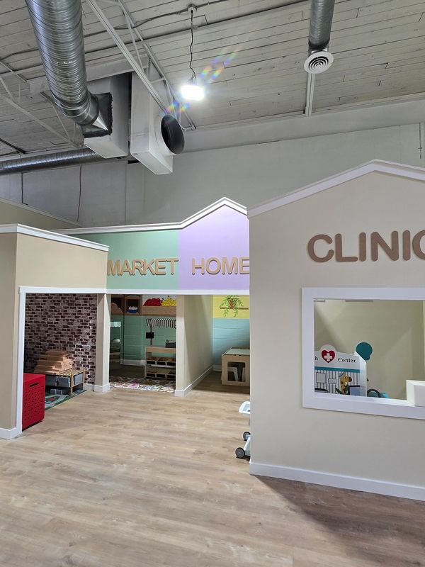 Indoor play area with sections labeled Clinic, Market, and Home.