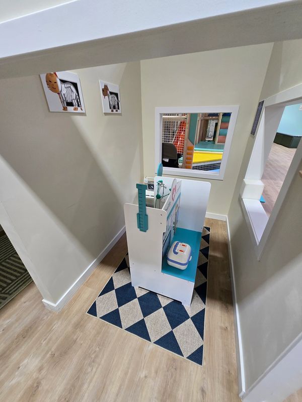 Children's play area with a small medical-themed play station and animal pictures on the wall.