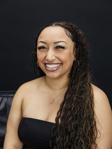 Smiling woman with curly hair and hoop earrings.