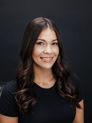 Smiling woman with long dark hair against a black background.