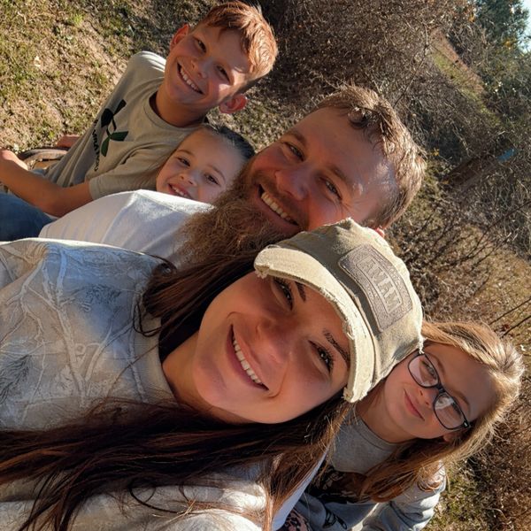 A happy family of five posing outdoors on a sunny day.