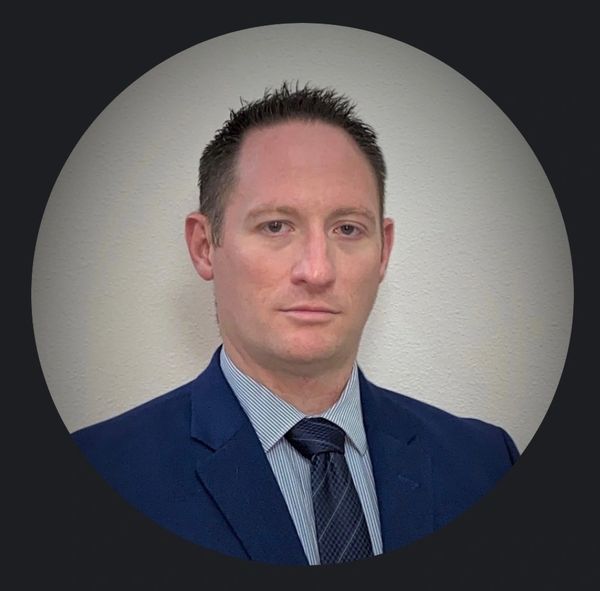 Professional man in a suit and tie against a plain background.