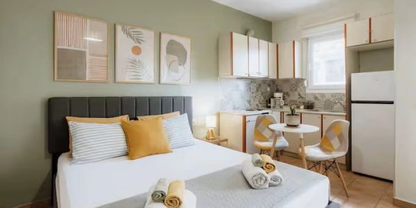 Cozy studio apartment with a bed, kitchenette, and dining area.