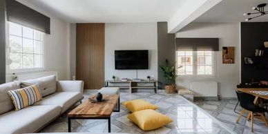 Modern living room with a white sofa, wooden coffee table, and TV mounted on the wall.