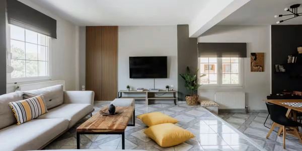 Modern living room with a white sofa, wooden coffee table, and TV mounted on the wall.