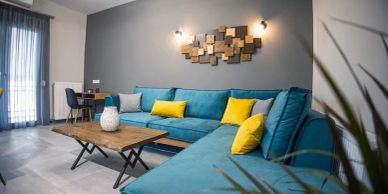 Modern living room with teal sectional sofa and yellow cushions.